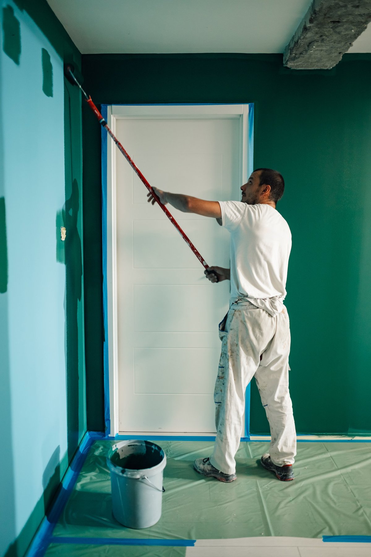 Pintor profesional aplicando pintura con rodillo en una pared
